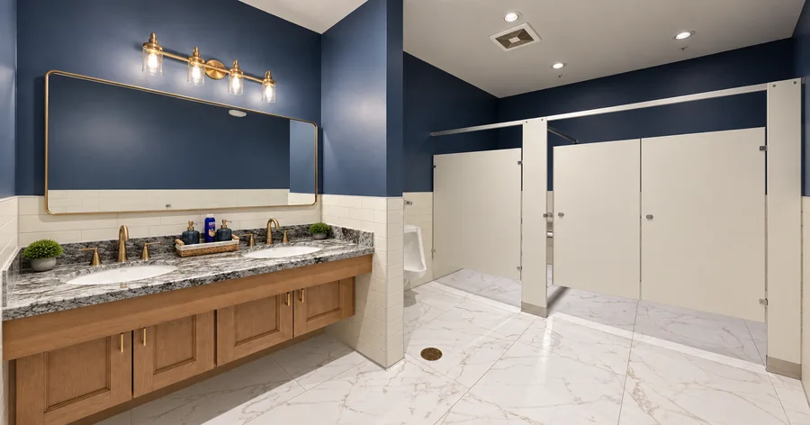 Financial Office Build-Out: Completed commercial restroom with blue feature walls, twin vanity, large mirror, marble-style floor and stalls