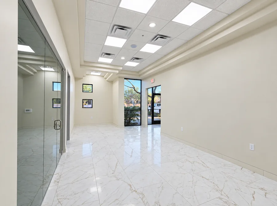 Financial Office Build-Out: Completed office entrance/corridor with glass-fronted room, marble-style flooring, paneled doors and ceiling soffit