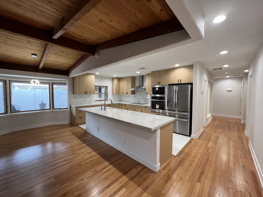 Home Renovation: Wide finished kitchen with a white island and exposed wood ceiling