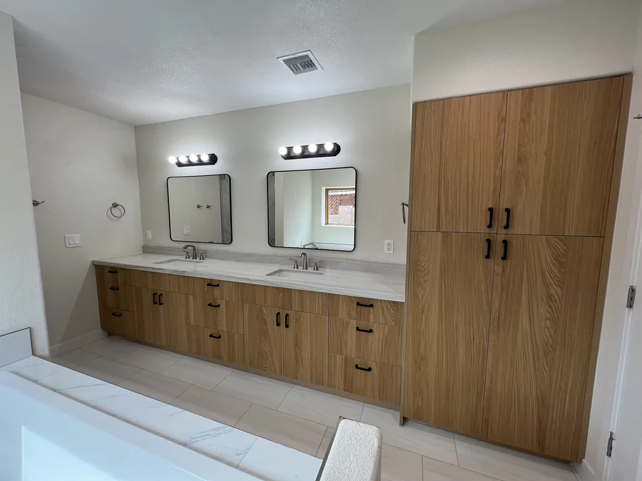 Home Renovation: Bathroom with double vanity, light wood cabinetry and marble-look finishes