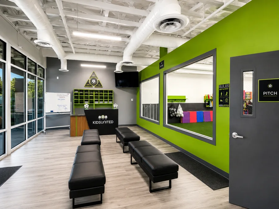 Kids United Sports Gym: Finished reception/check-in and waiting area with benches and large internal viewing window